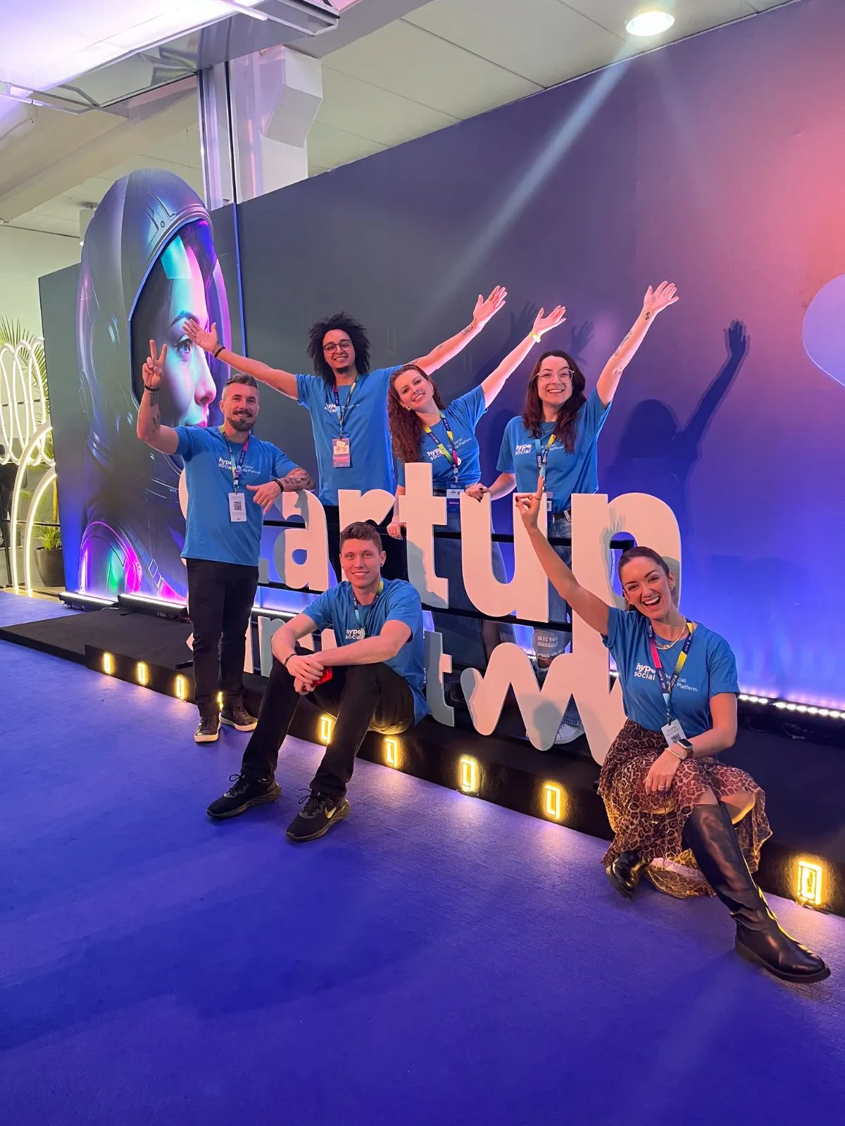 Equipe do Hype Social com camisetas da marca no letreiro do Startup Summit